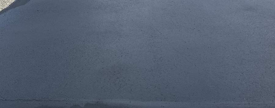 Close view of a freshly sealed asphalt driveway surface