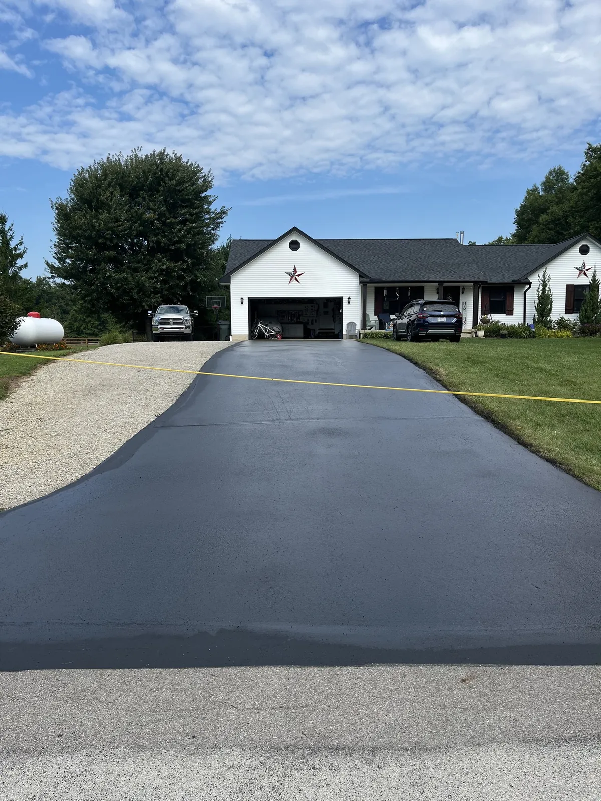 A fully sealed asphalt driveway taped off at the road, house behind it